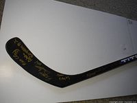 Signed blade of a black hockey stick with gold signatures from Team Quebec members including Maxime Oulette.