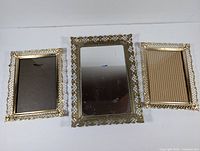 Photo showing two gold-toned lattice-edge frames and one matching mirror with visible surface markings.