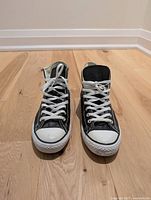 Front view of black leather Converse high tops showing white laces and toe caps.