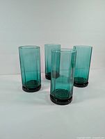 Four green decagon-shaped Anchor Hocking glass cups grouped together showing shape and color.