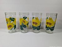 Photo of four vintage sunflower glass tumblers standing upright showing full sunflower design and overall condition.