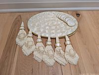 Capiz shell placemats, coasters, embroidered napkins with gold-tone napkin rings neatly arranged on wood surface
