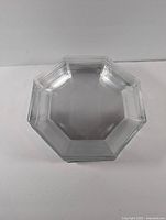 Single octagonal clear glass plate with stepped edge detailing on a white background.