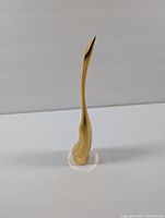 Front view of the brass crane figurine showing its polished elongated neck and smooth base.