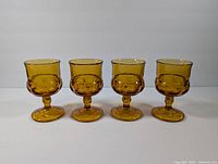 Set of 4 vintage amber Indiana Glass goblets showing front view, clearly displaying pattern and color.