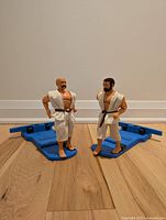 Front view of two vintage KAR-A-A-ATE Men by Aurora Toy G.I. Joe style action figures on blue controller bases