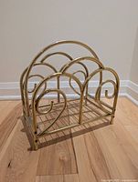 Front side view of the gold-toned metal magazine/vinyl rack showing the scroll design and curved arches.