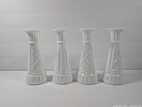 Front view showing the four milk glass vases in a row, highlighting the star pattern and consistent shape.