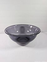 Side view of translucent blue Pyrex mixing bowl against white background, showing shape and color.