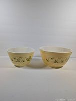Front view of two Pyrex Shenandoah mixing bowls placed side by side, showing their size difference and decorative floral pattern.