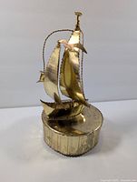 Front view of the vintage sailboat music box showing tarnished golden metal with detailed sails and birds.