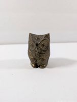 Front view of vintage small brass owl figurine showing detailed carved eyes and feathers.