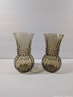 Front view of a pair of smoky glass swirl vases, showing shape and design