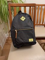 Front view of the dark grey WillLand Outdoors backpack on a chair, showing its design and condition.