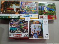 Photo of five assorted puzzles featuring various scenes and piece counts from 500 to 750.