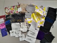 Overview of jewelry storage bags and pouches laid out on floor, including branded and fabric bags in assorted colors and sizes.