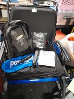 Front view of black and blue bariatric wheelchair with gel seat, backpack, and additional accessories on the seat.