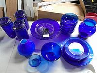 Photo showing entire assortment of cobalt blue glassware on table including canisters, bowls, vases and plates.