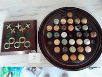 Wooden tic tac toe and solitaire games by Bombay Company shown on a marble surface.