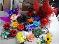 Various hair fascinators and floral hair accessories spread on a table. Showcases diversity of colors and styles including feathers, artificial flowers, and mesh accents.