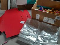 Red flat gift basket boxes, cellophane bags and assorted ribbons in a box