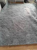 Full view of the large grey shag rug showing overall condition and texture.