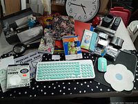 Top-down view showing assorted office supplies on a polka dot desk mat including wireless keyboard and mouse, note pads, CD/DVD sleeves, and stamps