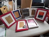Photo showing seven picture frames of various colors and conditions including one red frame still in packaging