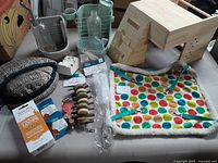Overview photo showing wooden hideout, fabric hammock bed, chew sticks, feeding troughs, water bottles, and packaged chew treats and tools.
