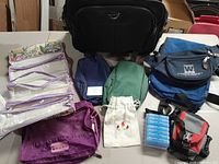 Full lot of assorted travel and toiletry bags displayed on table with various colors and styles.