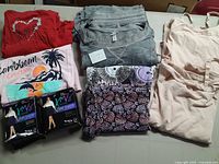 Red, grey, pink, and patterned plus size clothing including t-shirts, pants, shapewear tops, and nylons