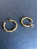 Both hoop earrings on black background, top view