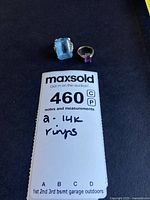 Two rings displayed on black background with MaxSold lot card visible