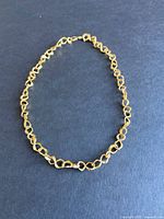 Full view of 18k gold choker chain laid flat on black background