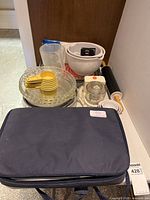 Full overview of baking kitchenware including measuring cups, glass pie dishes, casserole dish with bag, bowls, food chopper, and rolling pin.