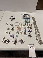 Photo showing the entire collection of costume jewelry pieces laid out on a white surface including earrings, pendants, a bracelet, and a long necklace.