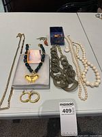Multiple costume jewelry pieces arranged on table including various necklaces, earrings, brooches and rings