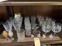 Full collection of crystal and glassware items arranged on a shelf, showing variety in shapes and sizes