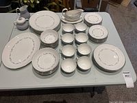 Full spread of dinnerware including platters, various plates, bowls, cups, saucers, sugar bowl, creamer and gravy boat on table