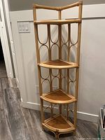 Front view of corner display shelving unit showing four triangular wooden shelves with rattan frame