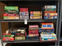 Photo showing several stacked board games and jigsaw puzzles on two shelves, including Woody Woodpecker puzzle, Mutual Mania game, Springbok puzzles, Trivial Pursuit and more.