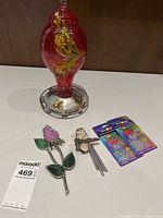 Front and angled views of decorative blown glass hummingbird feeder, stained glass tulips, owl wind chime, and decorative beads.