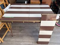 Full view of retro kitchen table with striped brown and white pattern and attached metal legs