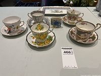 Front view of the five teacups with matching saucers and the small rectangular serving platter on a table.