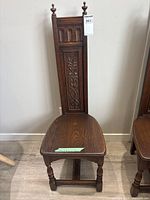 Full front view of the vintage carved oak hall chair showing entire chair including the tall backrest with ornate carvings and the carved legs.