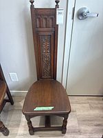 Full view of the vintage carved oak hall chair showing high backrest with carvings and wooden seat.
