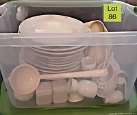 Large plastic bin filled with a stack of vintage and antique white plates, bowls, pitchers, ladles, and more kitchenware items, showing assortment and condition