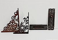 Photo showing two Victorian cast iron shelf brackets, letter mail slot, and door plate arranged side by side on white background.