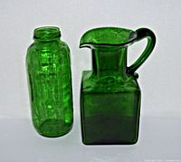 Photo showing front view of green glass bottle and square glass pitcher