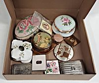 Box containing all 12 vintage vanity items including trinket boxes, powder jars, compacts, cigarette holder, hair receiver and papier poudre.